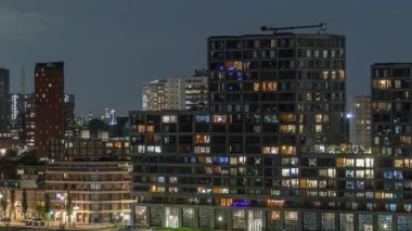 Geceleri Katendrecht yarımadasının panoramik zaman çizelgesi ve Hollanda Rotterdam 'daki Maashaven limanı. Aydınlatılmış şehir silüeti, modern gökdelenler ve Europole, rıhtımdaki evler