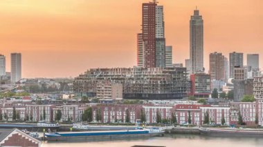 Günbatımında Rotterdam şehir merkezindeki modern binaların hava zaman çizelgesi, Hollanda. Finans bölgesinde kuleler ve gökdelenler, turuncu gökyüzü ile eski fabrika canlı bir ufuk çizgisi oluşturur