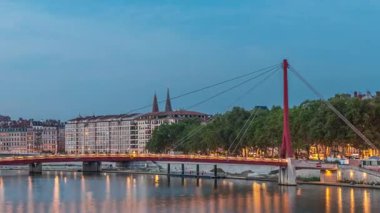 Lyon 'daki Saone Nehri' nin üzerindeki Palais du Justice Köprüsü 'nde, günden geceye geçiş. Rıhtımdaki aydınlık binalar gün batımından sonra suya yansıyor.