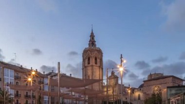 İspanya, Valencia 'daki Plaza de la Reina' da panoramik günden geceye geçiş süreleri aşırı hızlanıyor. Tarihi bir kilise kulesi, hareketli kafeleri ve akşam gökyüzünün altında merkezi bir çeşmesi olan canlı bir meydan..