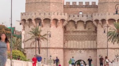 Serrans Kuleleri Torres de Serranos zamanapse Valencia, İspanya 'da. Şehrin antik duvarlarından gelen büyük bir ortaçağ kapısı. İnsanlar gün batımından önce tarihi bir dönüm noktasında köprüde yürüyorlar.