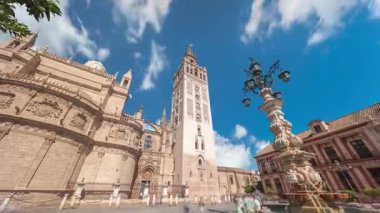 Virgen de los Reyes Meydanı, Seville Katedrali ve Giralda Kulesi zaman atlamalı Seville, İspanya 'da. Dünyanın en büyük gotik katedrali, mavi bulutlu gökyüzünün altındaki UNESCO miras alanı.