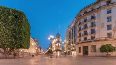 Avenida de la Constitucion, Seville, İspanya 'da günden geceye zaman dilimi. Modern sokak lambaları, yayalar ve kentsel atmosferi olan tarihi mimari. Iconic Adriatica binası gün batımından sonra parlıyor.
