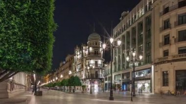 Avenida de la Constitucion gece vakti Seville, İspanya 'da aşırı hız. Iconic Adriatica binası akşam parlıyor. Modern sokak lambaları, yayalar ve şehir atmosferine sahip tarihi mimari