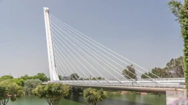 İspanya 'nın Sevilla kentindeki Guadalquivir Nehri' nin üzerinden geçen uzun kolon ve çelik kablolu Alamillo Köprüsü. Açık mavi gökyüzü altında yoğun trafik ile modern süspansiyon tasarımının hızlandırılmış zamanlaması.