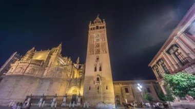La Giralda ve Seville Katedrali geceleri aşırı hızlanarak altın ışıklarla parıldıyor. Tarihi çan kulesi, gotik detaylar ve aydınlatılmış sokaklar Sevilla, İspanya 'da büyülü bir atmosfer yaratıyor.