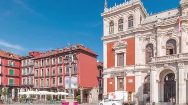 Panorama, Valladolid Plaza Belediye Başkanı Timelapse bayraklarıyla belediye binasının ön cephesini gösteriyor. Mavi gökyüzü ve şehrin göbeğindeki tarihi mimari. Yayalar bu merkez meydandan geçiyor..