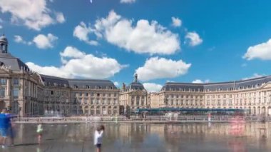 Place de la Bourse ve Miroir deau hiperlapse Bordeaux, Fransa 'da, tarihi mimariyi yansıtıyor. Turistler şehir simgesi ve çeşmenin tadını çıkarıyorlar. Trafik ve tramvay zamanı geçiyor..