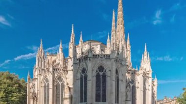 Saint-Andre de Bordeaux Katedrali. Mavi gökyüzünün altında ikiz kuleleri olan hızlandırılmış zaman atlaması. Yeşil ağaçlar ve meydanda yürüyen insanlar sakin bir şehir atmosferi yaratıyor. Bordeaux, Fransa