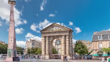 Fransa, Bordeaux 'da Place de la Victoire' da Porte dAquitaine kemeri ve dikilitaş. Tramvay hatları, kafeler ve mavi bulutlu gökyüzünün altında çevreleyen canlı Bordeaux 'nun tarihi simgesi.