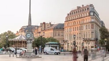 Günbatımında Place de la Comedie Timelapse, Bordeaux, Fransa 'da üçgen bina ve modern tramvay. Gölgeler ön cephede ilerler ve saatli bir sokak lambası bu şehir simgesine zarafet katar.
