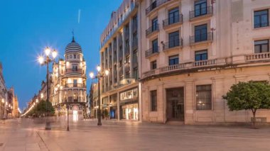 Avenida de la Constitucion, Seville, İspanya 'da günden geceye zaman dilimi. Modern sokak lambaları, yayalar ve kentsel atmosferi olan tarihi mimari. Iconic Adriatica binası gün batımından sonra parlıyor.