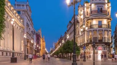 Avenida de la Constitucion, Seville, İspanya 'da günden geceye zaman dilimi. Iconic Adriatica binası gün batımından sonra parlıyor. Modern sokak lambaları, yayalar ve şehir atmosferine sahip tarihi mimari