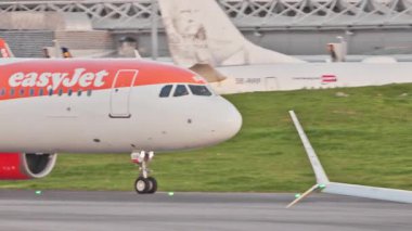 Ticari uçaklar Lizbon 'da yoğun bir havaalanının pistinde EasyJet taksiler, terminaller, diğer uçaklar ve arka planda bir şehir manzarası. Hava taşımacılığının ve havacılığın canlı atmosferi