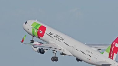 Lizbon Havaalanı 'ndan kalkan uçak. TAP Air Portugal uçaklarının yakın çekim görüntüleri açık mavi gökyüzünün altında şehrin ufuk çizgisi ve havaalanı altyapısı ile kalkıyor.