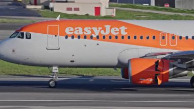 Lizbon Havaalanı 'na indikten sonra terminallere giden ticari bir uçak. Easy Jet Havayolları, güneşli bir günde arka planda şehir silueti ve havaalanı altyapısı ile taksiyollarına devam ediyor.