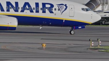 Lizbon Havaalanı 'na indikten sonra terminallere giden ticari bir uçak. Ryanair Havayolları, güneşli bir günde arka planda şehir silueti ve havaalanı altyapısı olan taksiler üzerinde hareket ediyor.