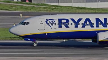 Lizbon Havaalanı 'na indikten sonra terminallere giden ticari bir uçak. Ryanair Havayolları, güneşli bir günde arka planda şehir silueti ve havaalanı altyapısı olan taksiler üzerinde hareket ediyor.