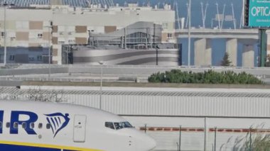 Lizbon Havaalanı 'na indikten sonra terminallere giden ticari bir uçak. Ryanair Havayolları, güneşli bir günde arka planda şehir silueti ve havaalanı altyapısı olan taksiler üzerinde hareket ediyor.