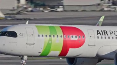 Lizbon Havaalanı 'ndan kalkan uçak. TAP Air Portugal uçaklarının yakın çekim görüntüleri açık mavi gökyüzünün altında şehrin ufuk çizgisi ve havaalanı altyapısı ile kalkıyor.