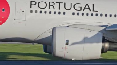 Lizbon Havaalanı 'ndan kalkan uçak. TAP Air Portugal uçaklarının yakın çekim görüntüleri açık mavi gökyüzünün altında şehrin ufuk çizgisi ve havaalanı altyapısı ile kalkıyor.