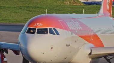 Ticari uçaklar Lizbon 'da yoğun bir havaalanının pistinde EasyJet taksiler, terminaller, diğer uçaklar ve arka planda bir şehir manzarası. Hava taşımacılığının ve havacılığın canlı atmosferi