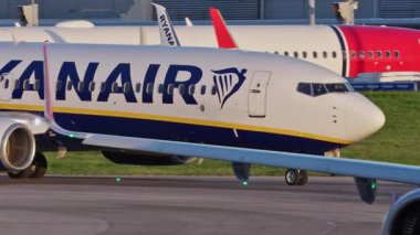 Ticari uçaklar Ryanair ve Wizzair, yoğun bir Lizbon havaalanının pistinde, terminaller, diğer uçaklar ve arka planda bir şehir manzarasıyla birlikte. Hava taşımacılığının ve havacılığın canlı atmosferi