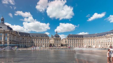 Place de la Bourse ve Miroir d 'eau hiperlapse Bordeaux, Fransa' da, tarihi mimariyi yansıtıyor. Turistler şehir simgesi ve çeşmenin tadını çıkarıyorlar. Trafik ve tramvay zamanı geçiyor..