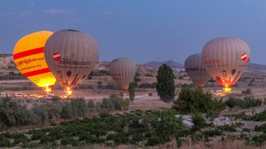Türkiye 'nin Kapadokya kentindeki alışılmadık kayalık zaman dilimi üzerinde güzel renkli sıcak hava balonları havalanıyor ve açık bir sabah gökyüzünde uçuyor.