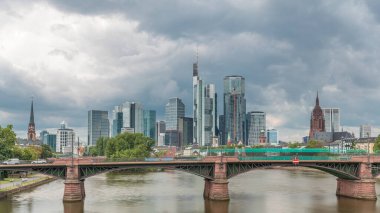 Frankfurt 'un, ana nehir ve Ignatz Bubis Köprüsü' yle olan hiperhızlandırılmış silueti. Gökdelenler ve kilise kuleleri dramatik bulutların altındaki suya yansıyor. Frankfurt, Almanya