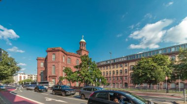 Frankfurt, Almanya 'da St. Paul Kilisesi (Paulskirche) zaman atlaması. Protestan kilisesi Paulplaz 'da duruyor. Bulutlarla kaplı mavi gökyüzünün altındaki bu tarihi anıtın etrafında sokak trafiği akıyor.
