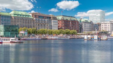 Almanya, Hamburg 'daki Binnenalster zaman ölçümüne bakın. Alster Gölü 'nün iç sularına yansıyan tarihi binalar mavi gökyüzünün altında. Gemili ve rıhtımlı manzaralı şehir manzarası
