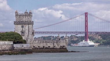 Lizbon, Portekiz 'de 25 Nisan Köprüsü' nde geçmişi olan Belem 'in Panorama' sı. Torre de Belem ya da Belem Kulesi ve Tagus nehri üzerinde kırmızı sembolik 25 de Abril Köprüsü olan şehir manzarası. Bulutlu gökyüzü