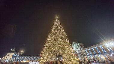 Lizbon 'daki ticaret meydanı, Noel' in aşırı hızıyla aydınlandı. Yükselen bir ağaç ve geceleri kutlayan kalabalıkla. Dekorasyon ve tarihi mimarinin yer aldığı şenlikli atmosferin zamanlaması