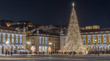 Lizbon 'daki ticaret meydanı, Noel' in aşırı hızıyla aydınlandı. Yükselen bir ağaç ve geceleri kutlayan kalabalıkla. Bir tepenin üzerindeki şenlikli atmosfer dekorasyonları ve tarihi mimarinin zamanı.