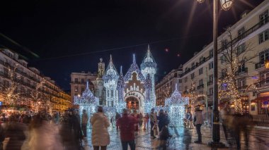 Lizbon, Portekiz 'deki Luis de Camoes meydanında aydınlatılmış şatoyla Noel süslemelerinin gece süreleri. İnsanlar şenlikli ışıkların ve tarihi mimarinin etrafında dolanıyor. Ön görünüm