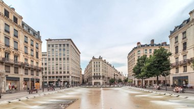 Fransa 'nın Lyon şehrindeki Place de la Republique' in hiperlapesi. Meydanda, tarihi binalarla çevrili büyük bir çeşme var ve insanlar banklarda oturuyor.