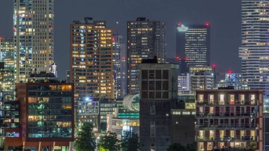 Rotterdam şehir merkezi, Hollanda 'daki modern binaların uçuş zamanı. Finans bölgesinde aydınlık kuleler ve gökdelenler. Parlayan pencereler, parlak bir gece silueti oluşturuyor.