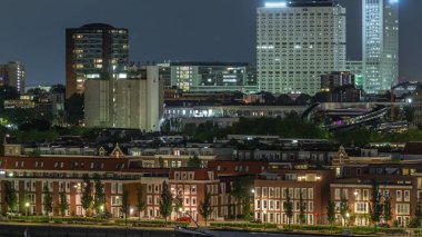 Geceleri Katendrecht yarımadasının panoramik zaman çizelgesi ve Hollanda Rotterdam 'daki Maashaven limanı. Aydınlatılmış şehir silüeti ve modern kuleleri olan geleneksel Hollanda rıhtım evleri