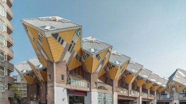 Rotterdam 'daki Küp Evi' nin (Kubuswoningen) hiperlapesi. Eşsiz sarı küp şekilli evler şehrin zaman dilimi içinde yenilikçi mimari sergiliyor. Mavi gökyüzü ve şehir canlılığı. Hollanda