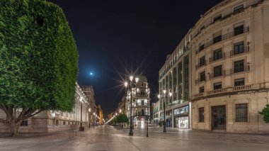 Avenida de la Constitucion gece vakti Seville, İspanya 'da aşırı hız. Iconic Adriatica binası akşam parlıyor. Modern sokak lambaları, yayalar ve şehir atmosferine sahip tarihi mimari