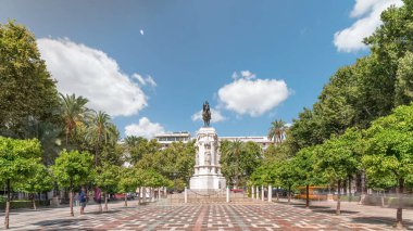 Seville 'deki Plaza Nueva' da, yeşil ağaçlar ve tarihi binalarla çevrili Kral San Fernando 'nun binicilik heykeli yer alıyor. Mavi gökyüzünün altında manzaralı bir şehir alanı