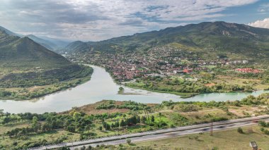 Kura ya da Mtkvari ve Aragvi nehirlerinin tek bir zaman diliminde birleşmesinin havadan görüntüsü. Gürcistan 'ın eski başkenti Mtskheta (sağda). Şehrin güzel manzarası, Georgia. Bulutlar geçip gidiyor
