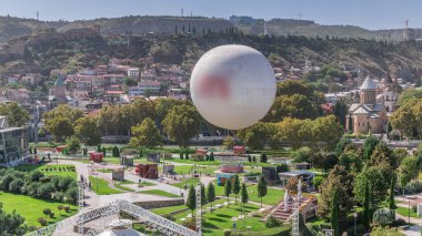 Yukarıdan Rike Park 'a. Tiflis 'in eski bir kasabasındaki modern şehir parkı. Şehirdeki dinlenme bölgesinde yeşil ağaçlar ve çimenler. Sıcak hava balonu ve teleferik. Georgia