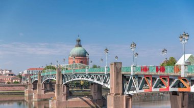 Garonne Nehri 'nin üzerindeki Saint Pierre Köprüsü' nde su ve La Grave Hastanesi 'nin arka planında bulutlu mavi bir gökyüzünün altında yansımaları var. Klasik sokak lambaları cazibe katar. Toulouse, Fransa