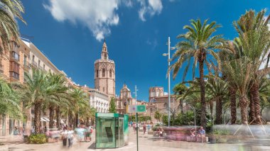 Valencia, İspanya 'da Plaza de la Reina' nın panoramik zaman atlaması. Tarihi bir kilise kulesi, hareketli kafeler ve sıcak Akdeniz semaları altında palmiyeleri olan merkezi bir çeşme..