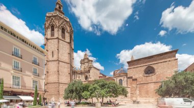 Valencia, İspanya 'da Plaza de la Reina' nın panoramik zaman atlaması. Tarihi bir kilise kulesi, hareketli kafeler ve sıcak Akdeniz mavi bulutlu gökyüzünün altında merkezi bir çeşme ile dolu canlı bir meydan..