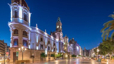 Valencia Belediye Binası (Ajuntament de Valencia) Plaza de Ayuntamiento 'da günden geceye geçiş zamanaşımı üst sürati. Saat kulesi olan tarihi bir bina. İspanya 'nın ana meydanında gezinen insanlar