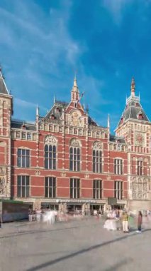 Amsterdam Merkez Tren İstasyonu 'nda tarihi bir girişi olan hiperlapse. Bir sürü yolcu zaman içinde girip çıkıyor. Mavi gökyüzündeki bulutlar. Amsterdam, Hollanda