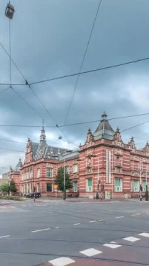 Amsterdam Stedelijk Müzesi modern ve çağdaş sanat eserlerini sergiliyor. Tramvay ve otobüslerle kavşaktan geçen trafik bulutlu bir zaman dilimi altında ilerliyor. Amsterdam, Hollanda